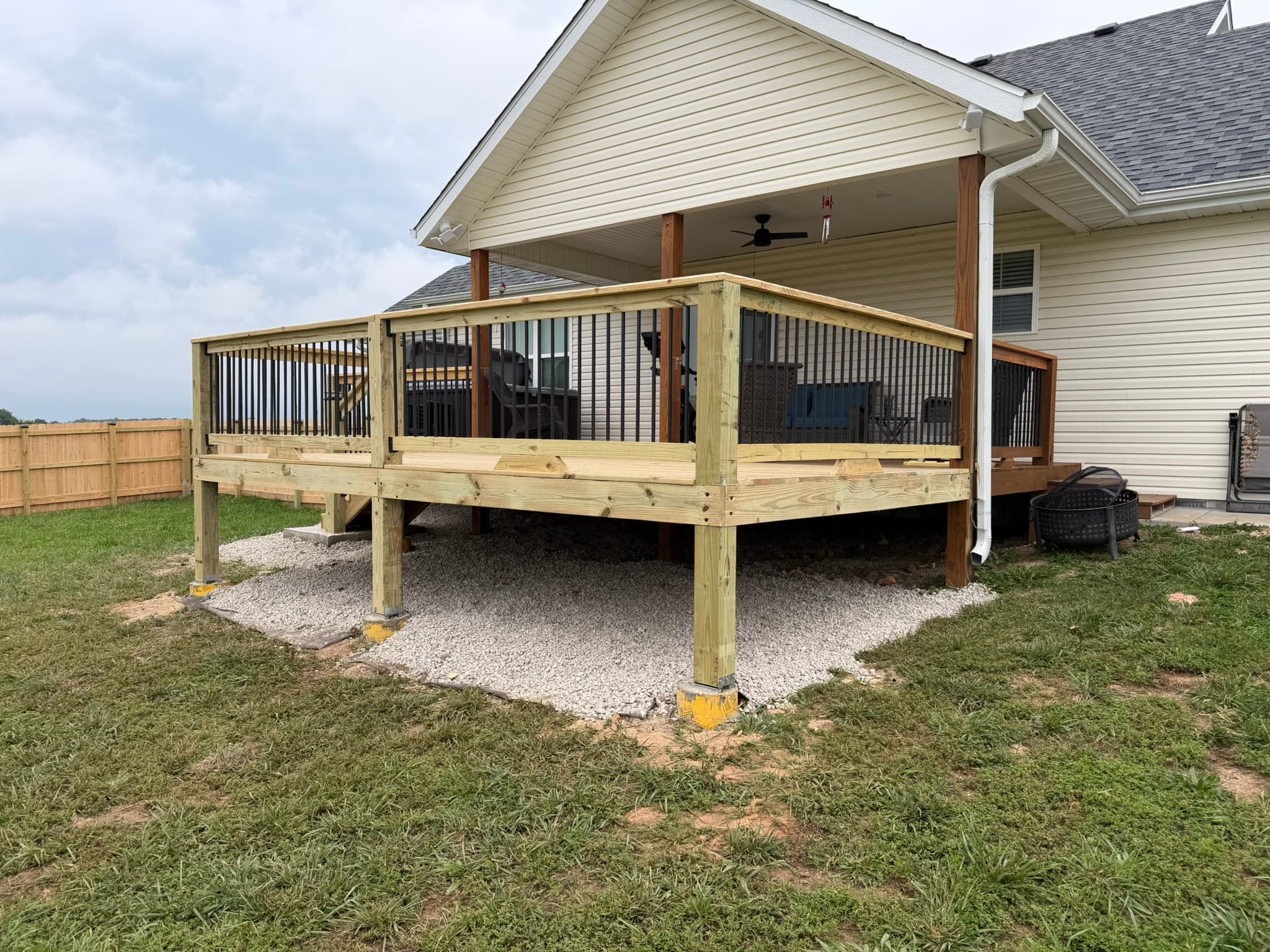 Completed pressure-treated backyard deck addition behind a suburban home