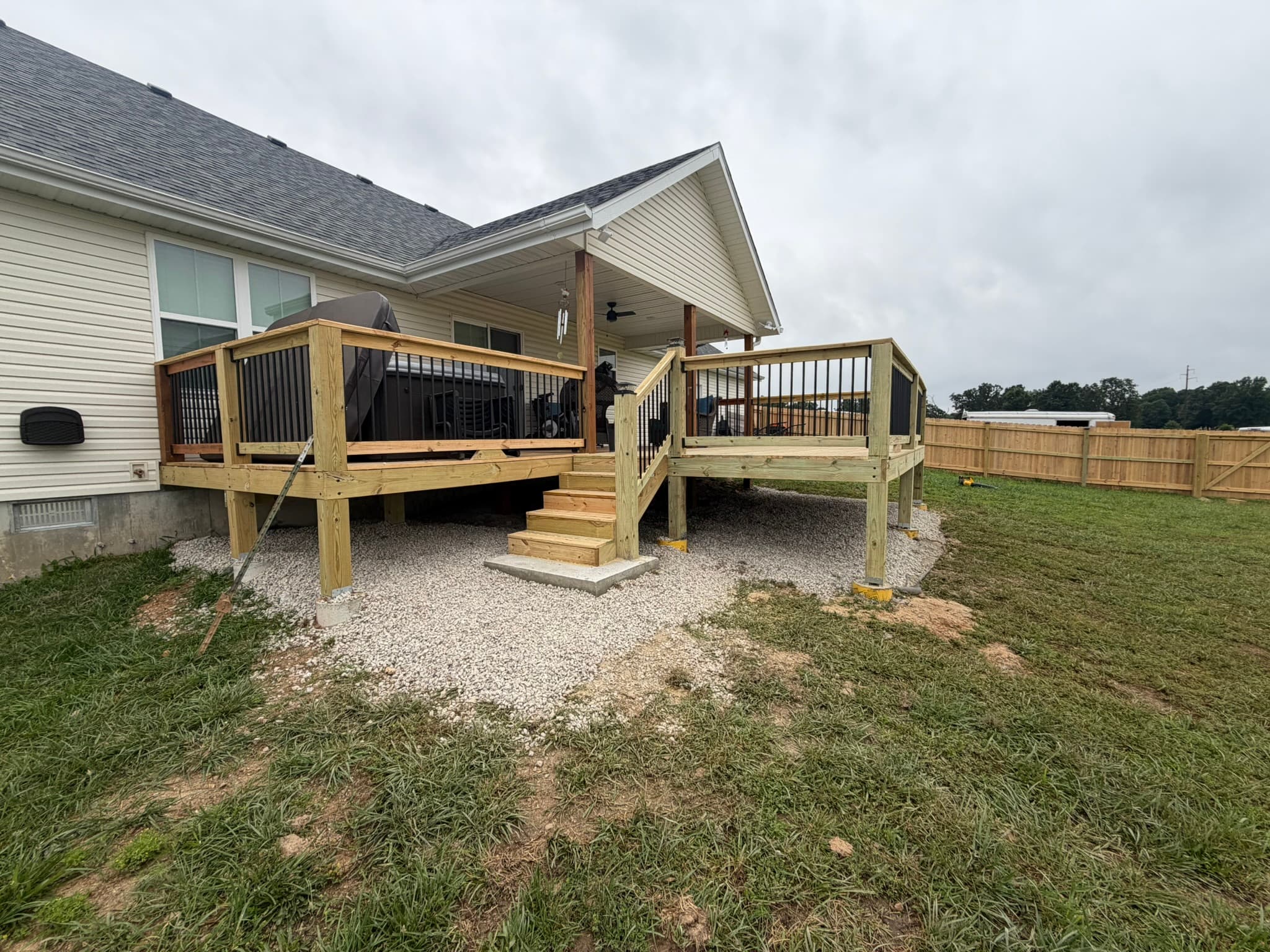 New elevated wood deck with stairs and railing at a residential backyard