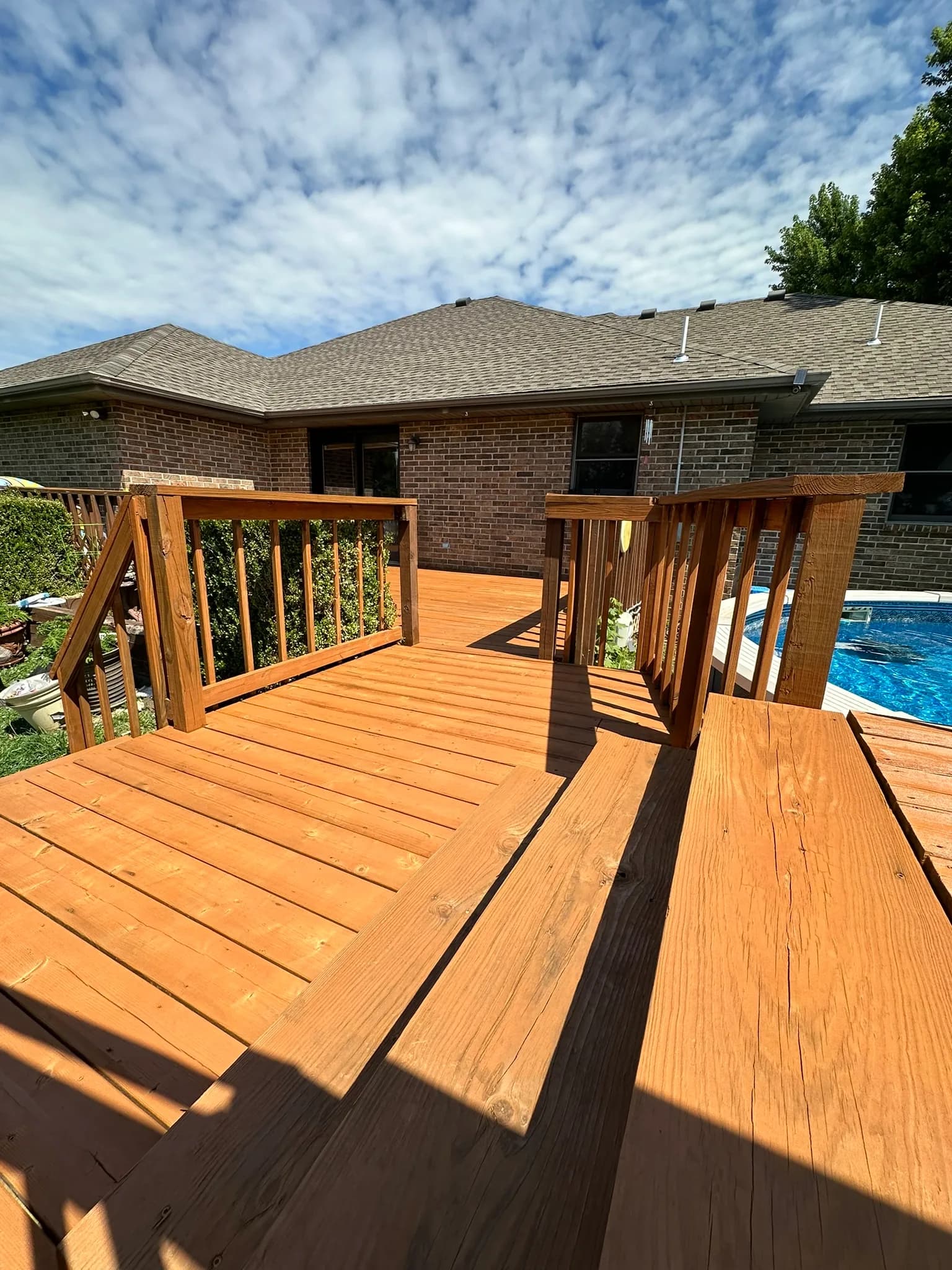 Pressure-treated pool deck with wood railing and a view across the backyard