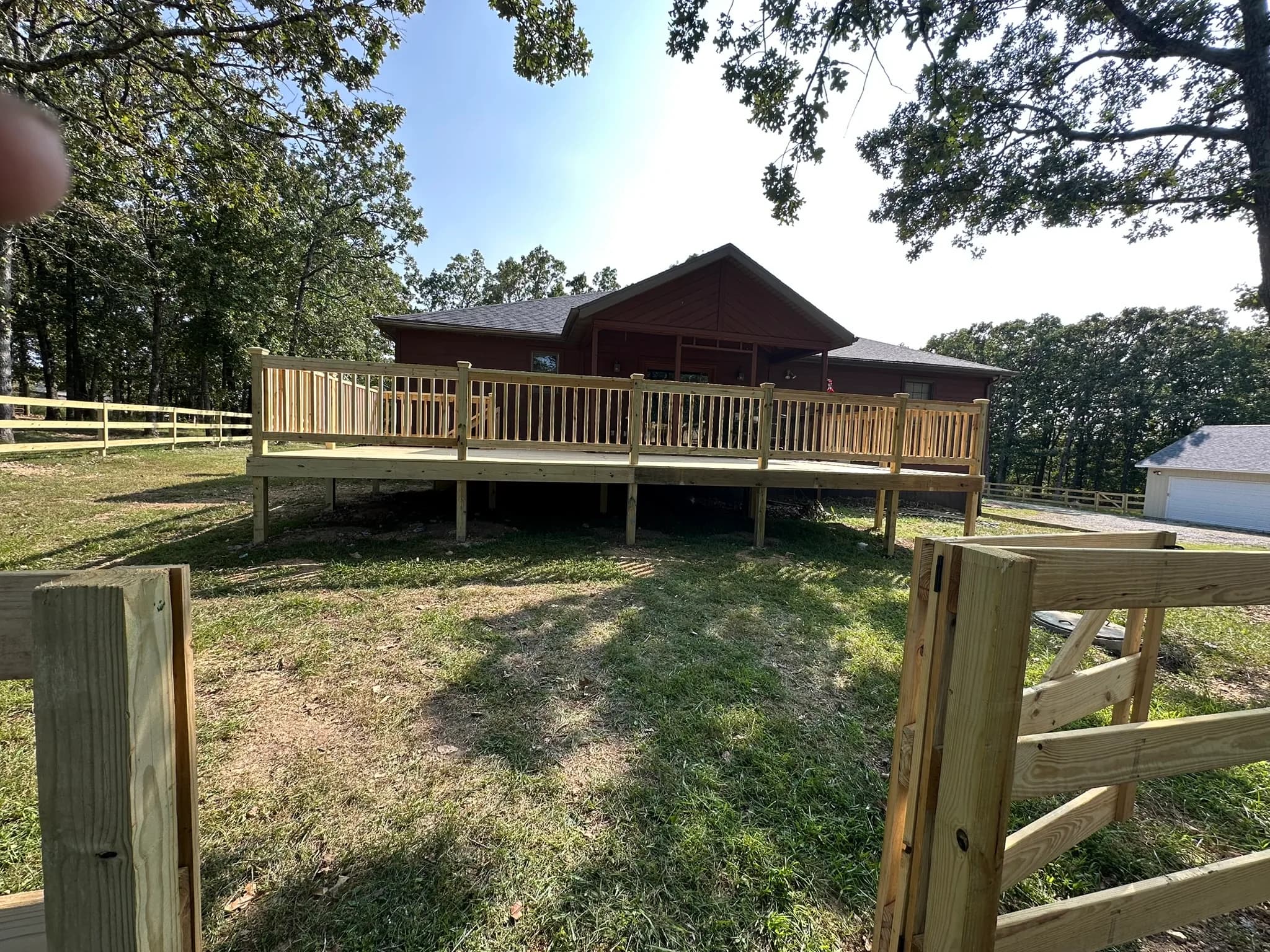 Raised backyard deck built around a home with steps to the yard