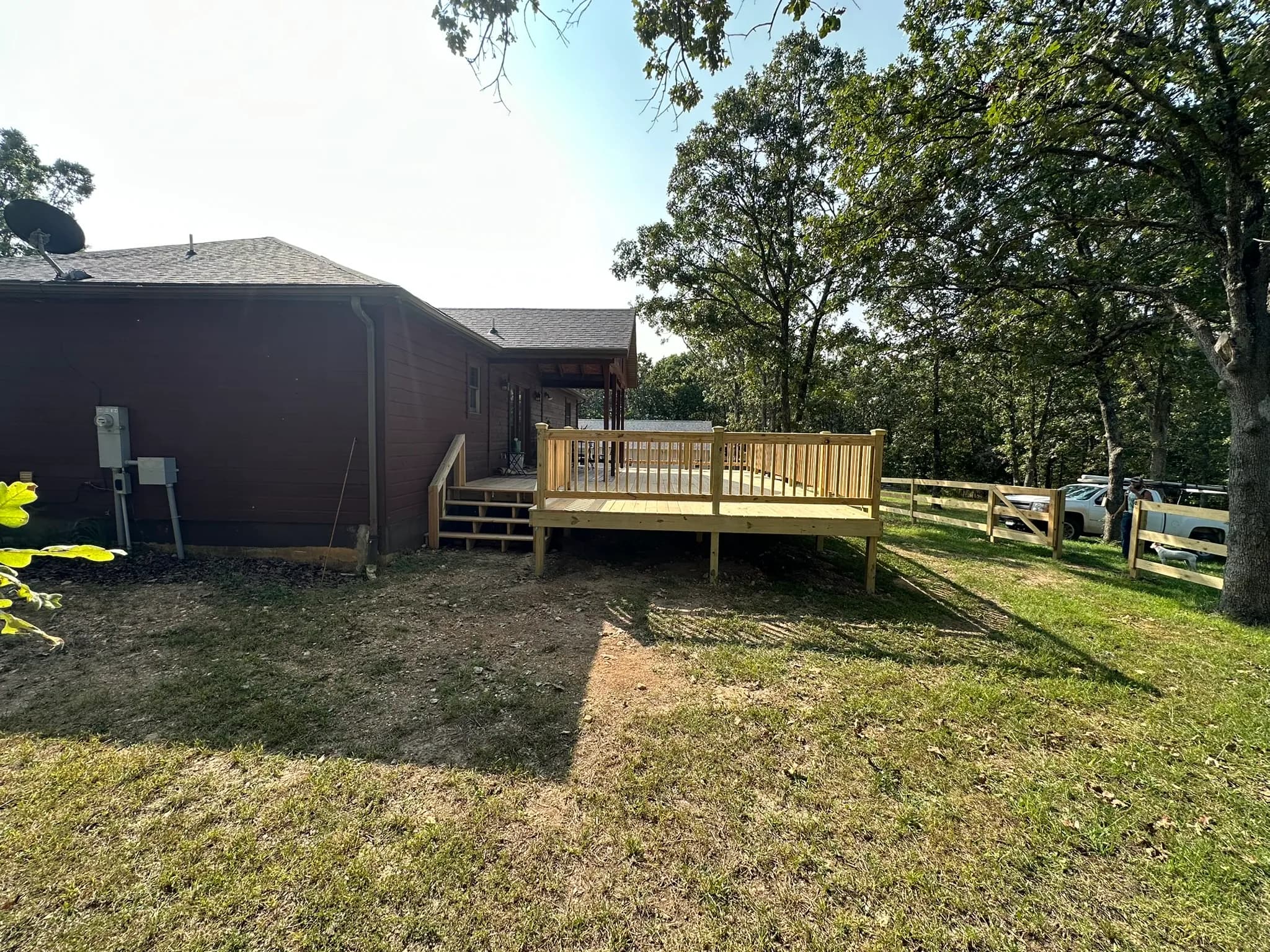 Wood deck expansion with new railing beside a residential home