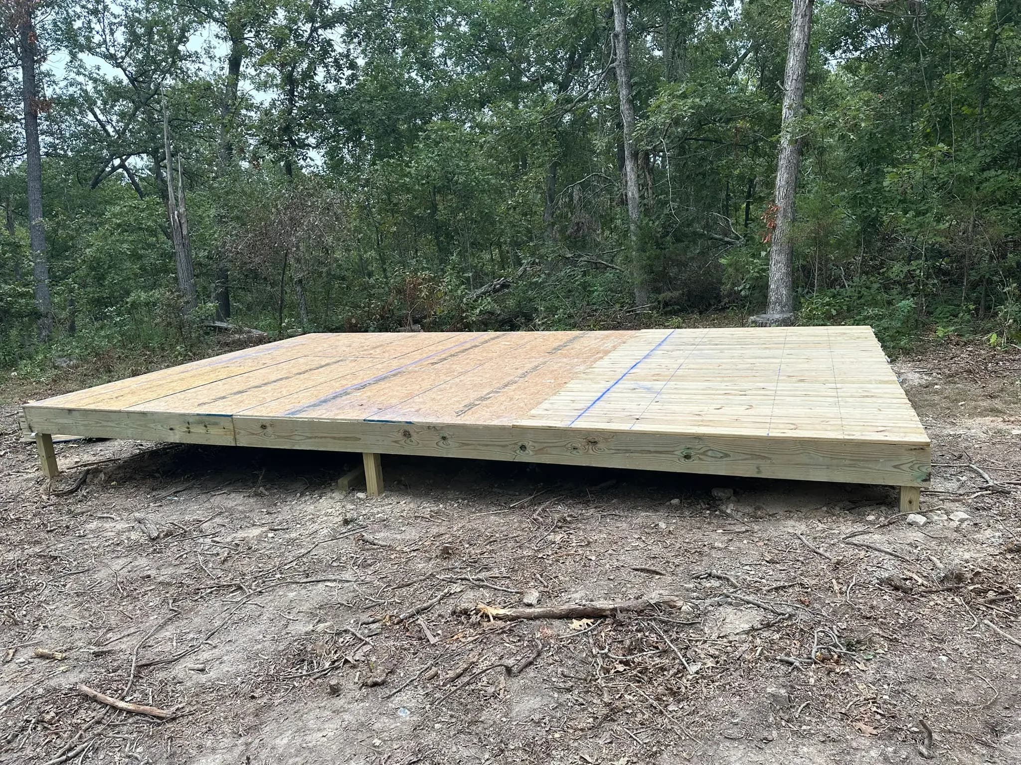 Low wood deck platform built on posts in a wooded area