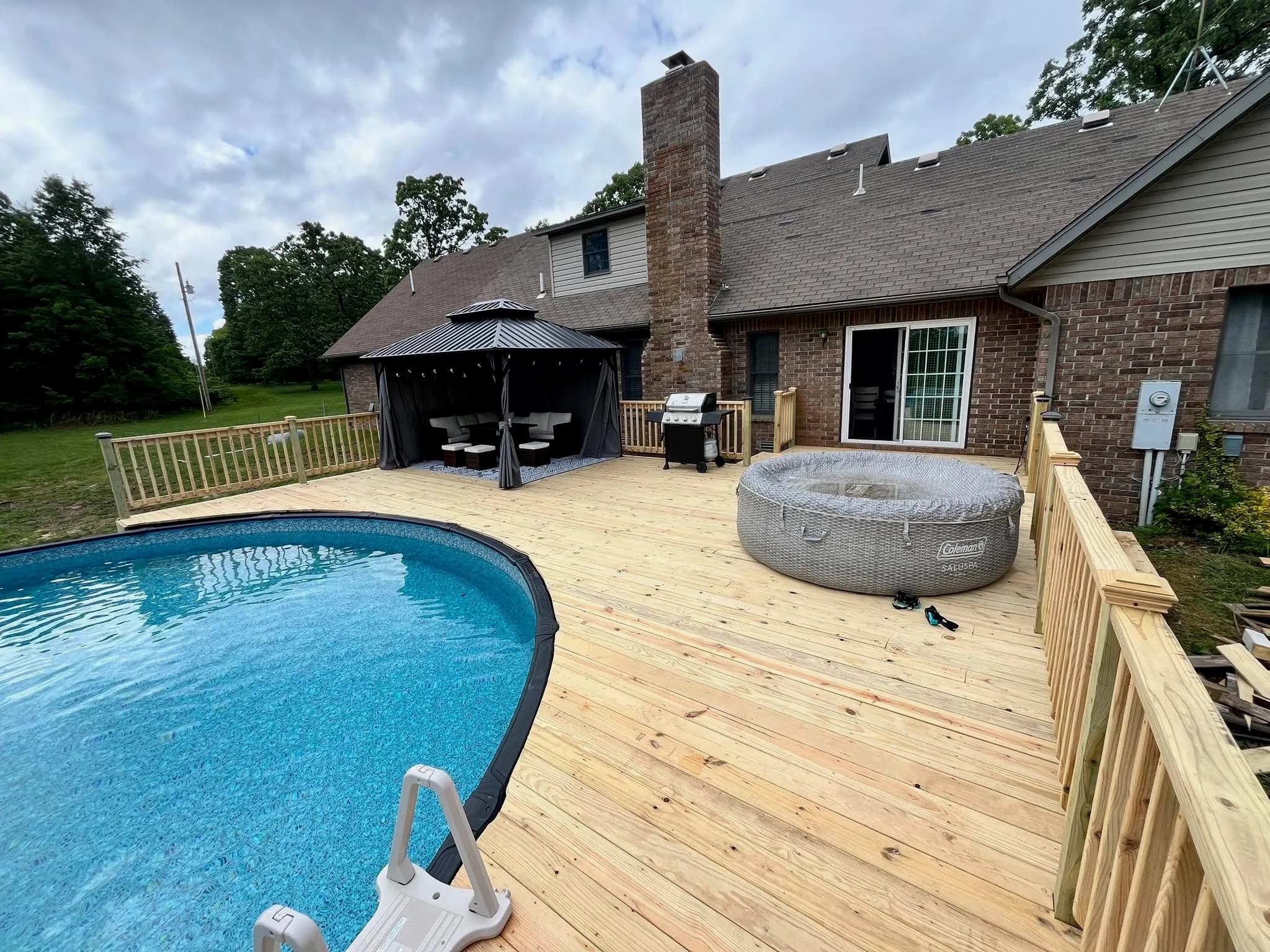 Large pressure-treated pool deck with railings built around an above-ground pool