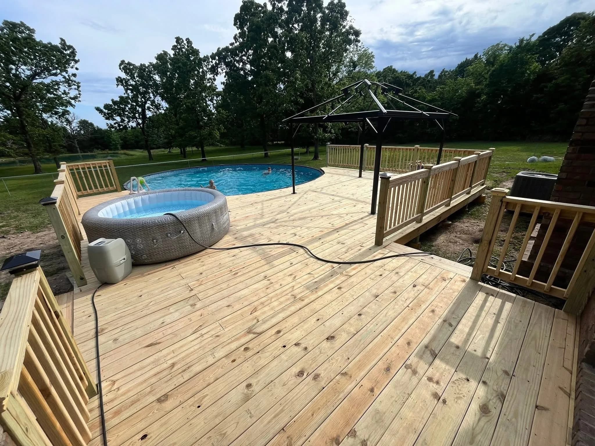 Completed backyard pool deck with wide wood boards and safety railing