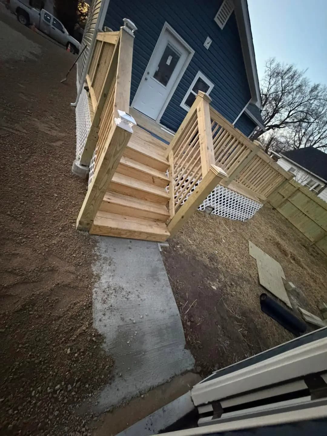 Wood deck stairs and railing built beside a blue house