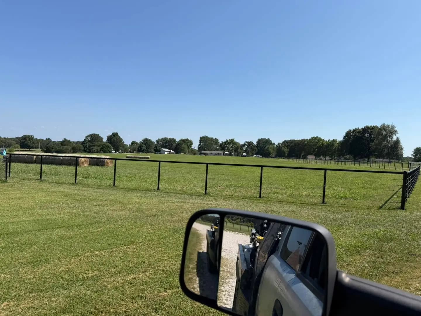 Black continuous fence line along a pasture driveway