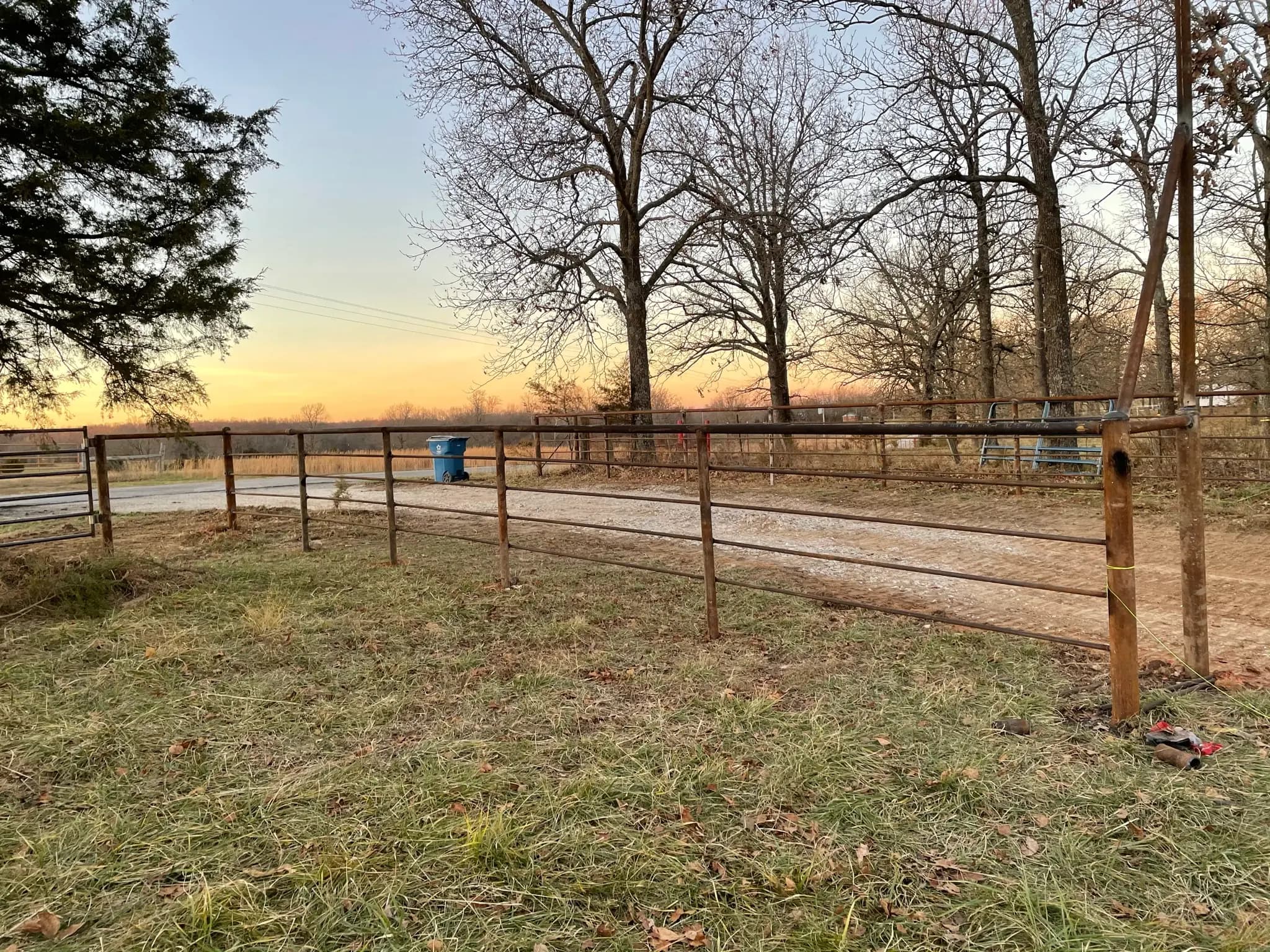 Pipe fence line across pasture at sunset