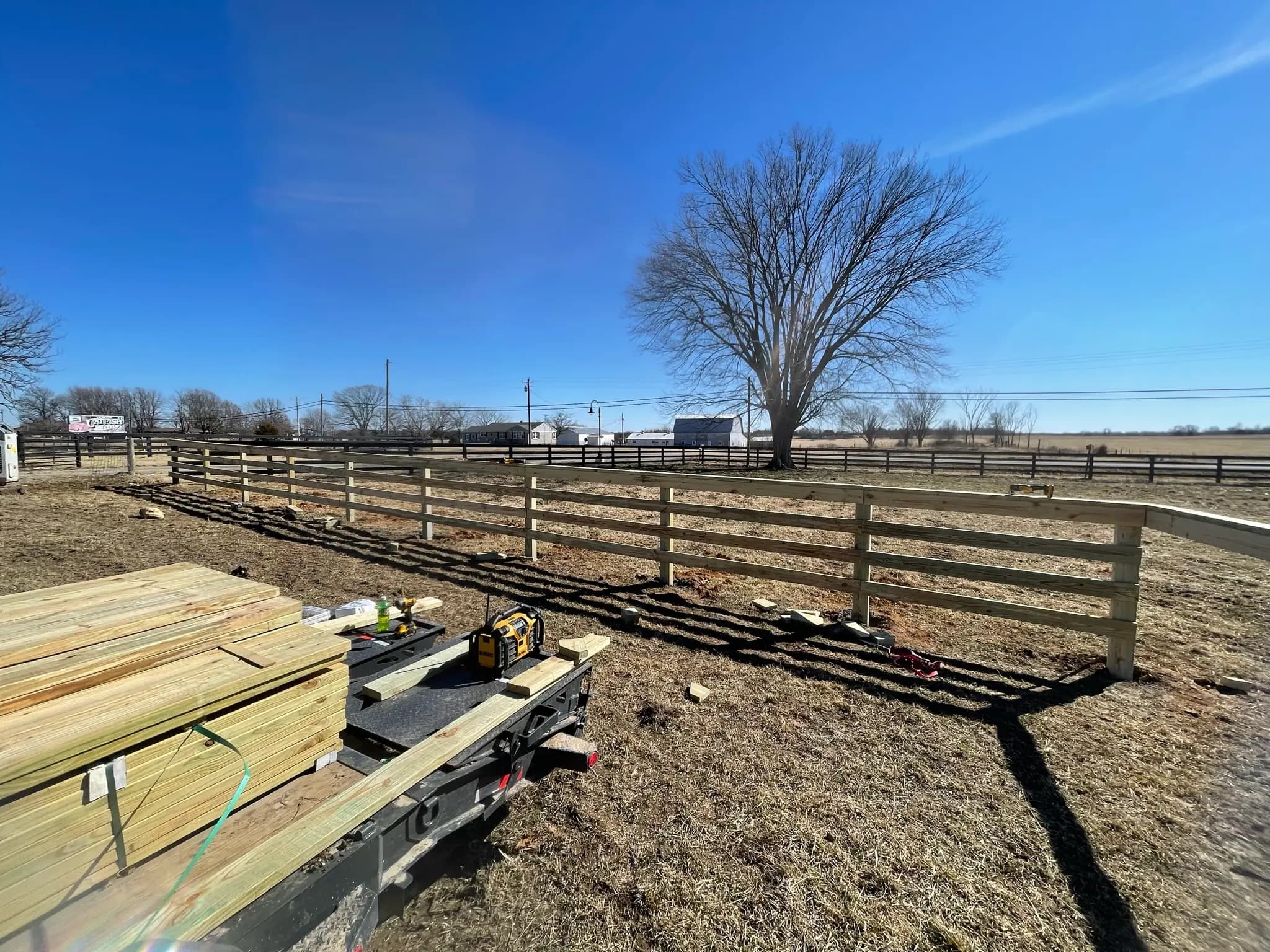 Continuous fence installation with lumber staged nearby
