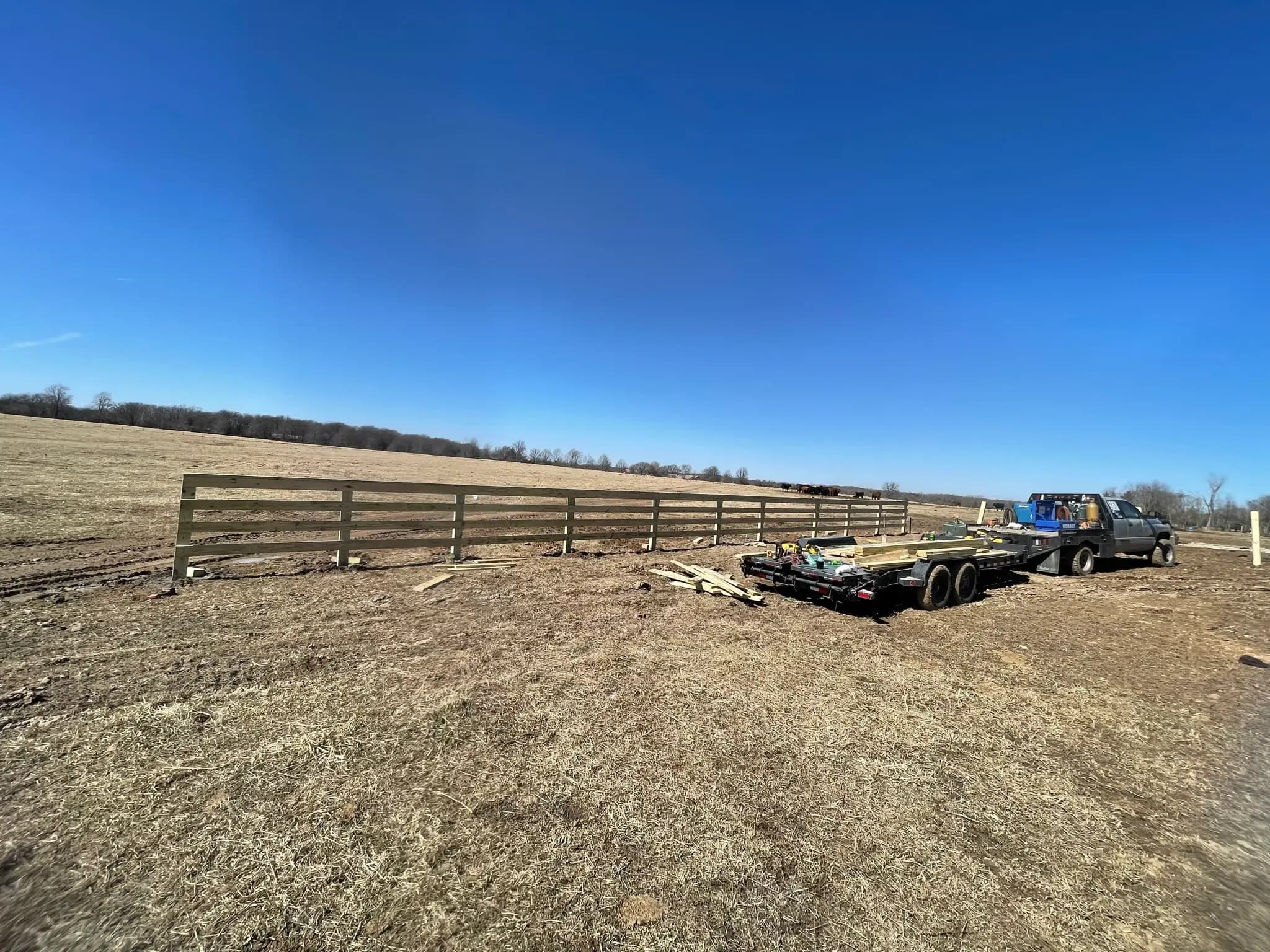 Long farm fence line installed across open ground
