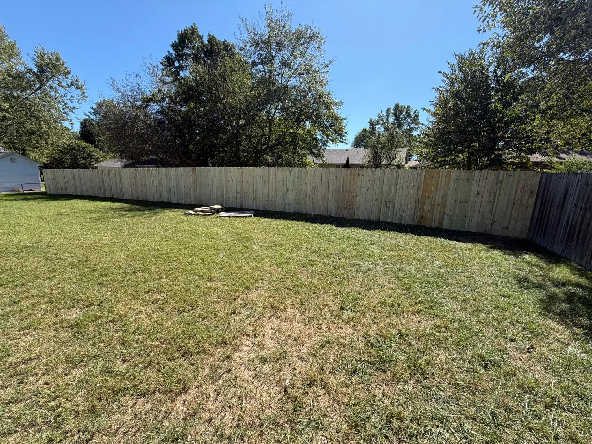 Wood privacy fence enclosing a shaded backyard