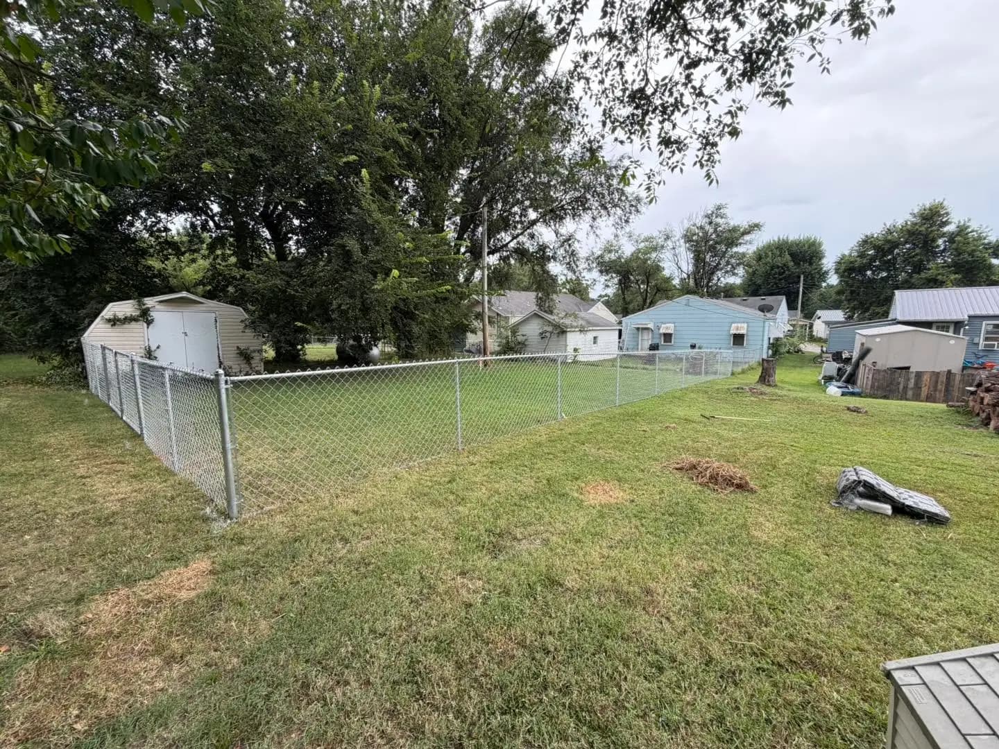 Chain link corner fence enclosing a backyard lawn