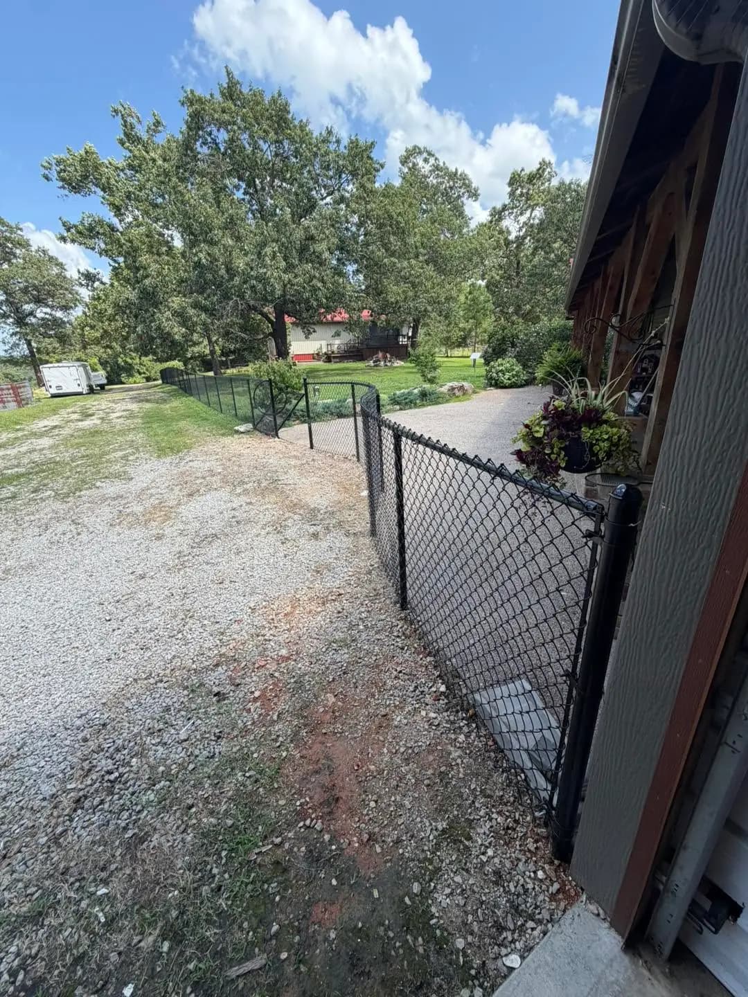 Black chain link gate opening from patio to gravel drive