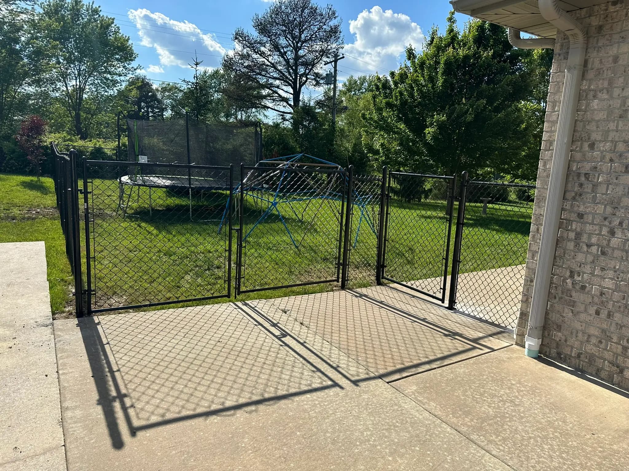 Double black chain link gate beside a brick building