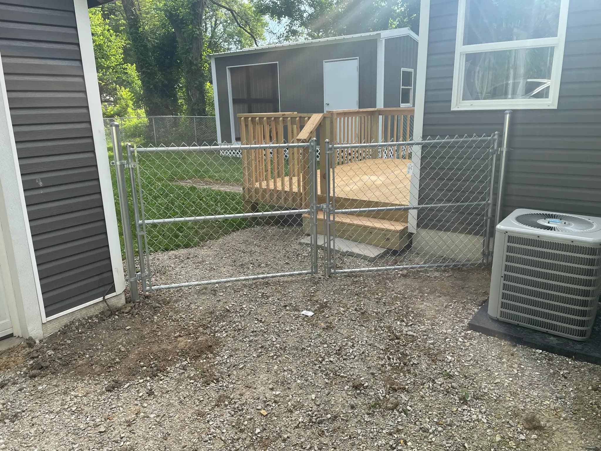 Chain link gate and small wood porch beside a home