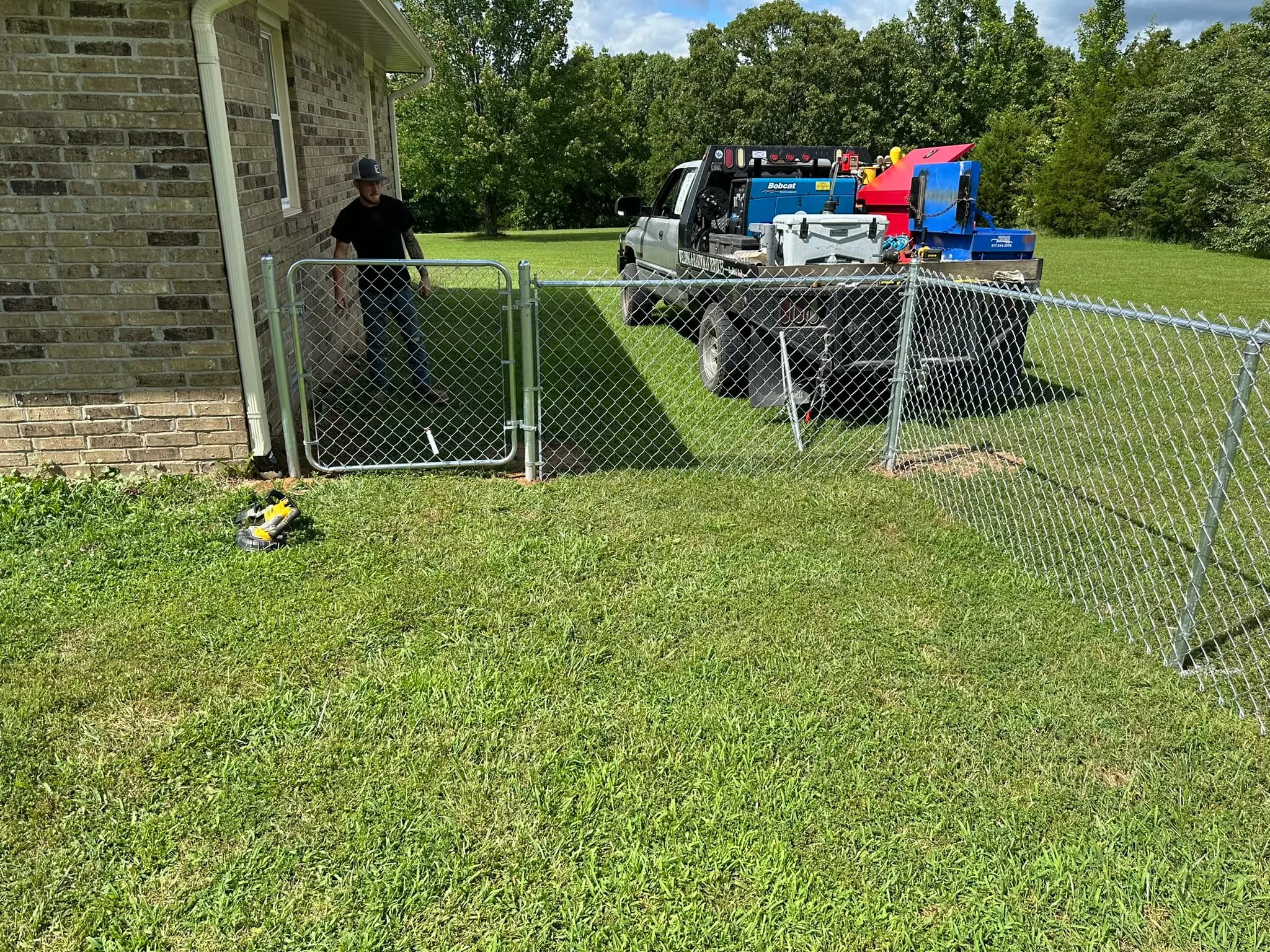 Chain link gate installed beside a house and work truck