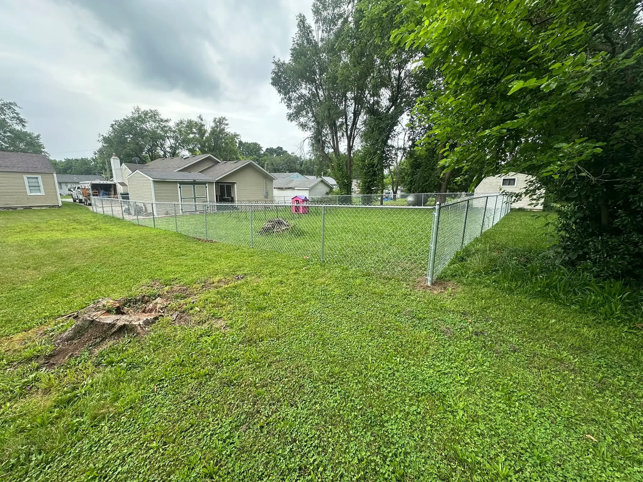 Chain link fence enclosing a broad backyard lawn