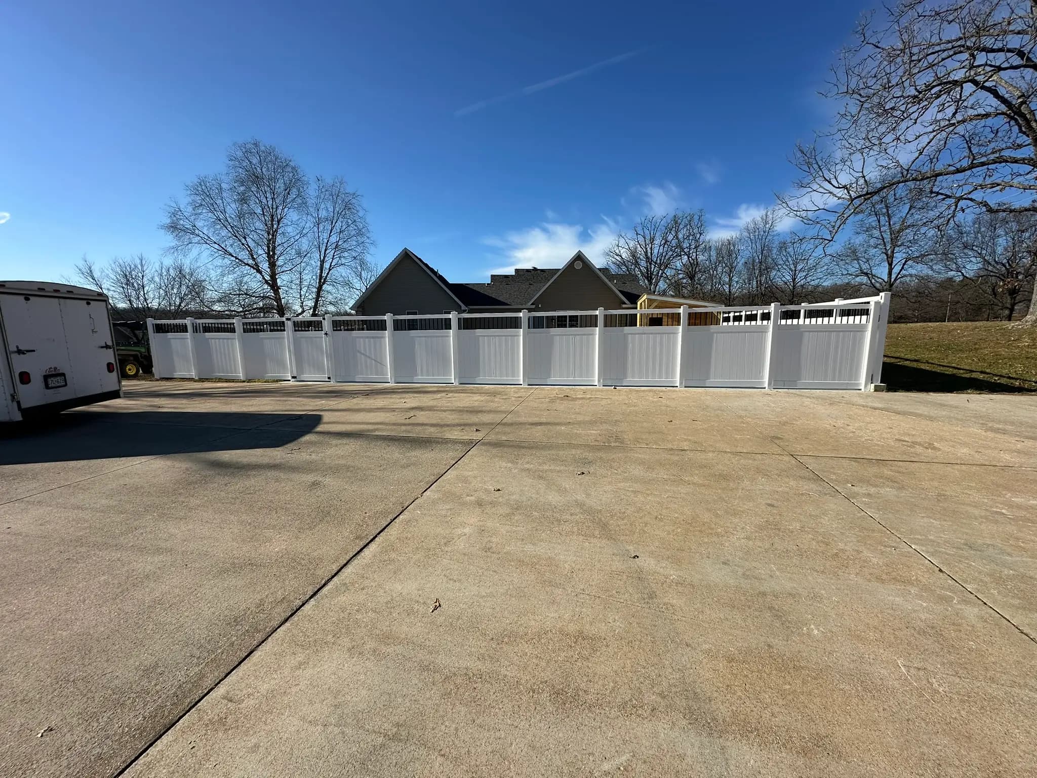 White vinyl privacy fence enclosing a concrete driveway