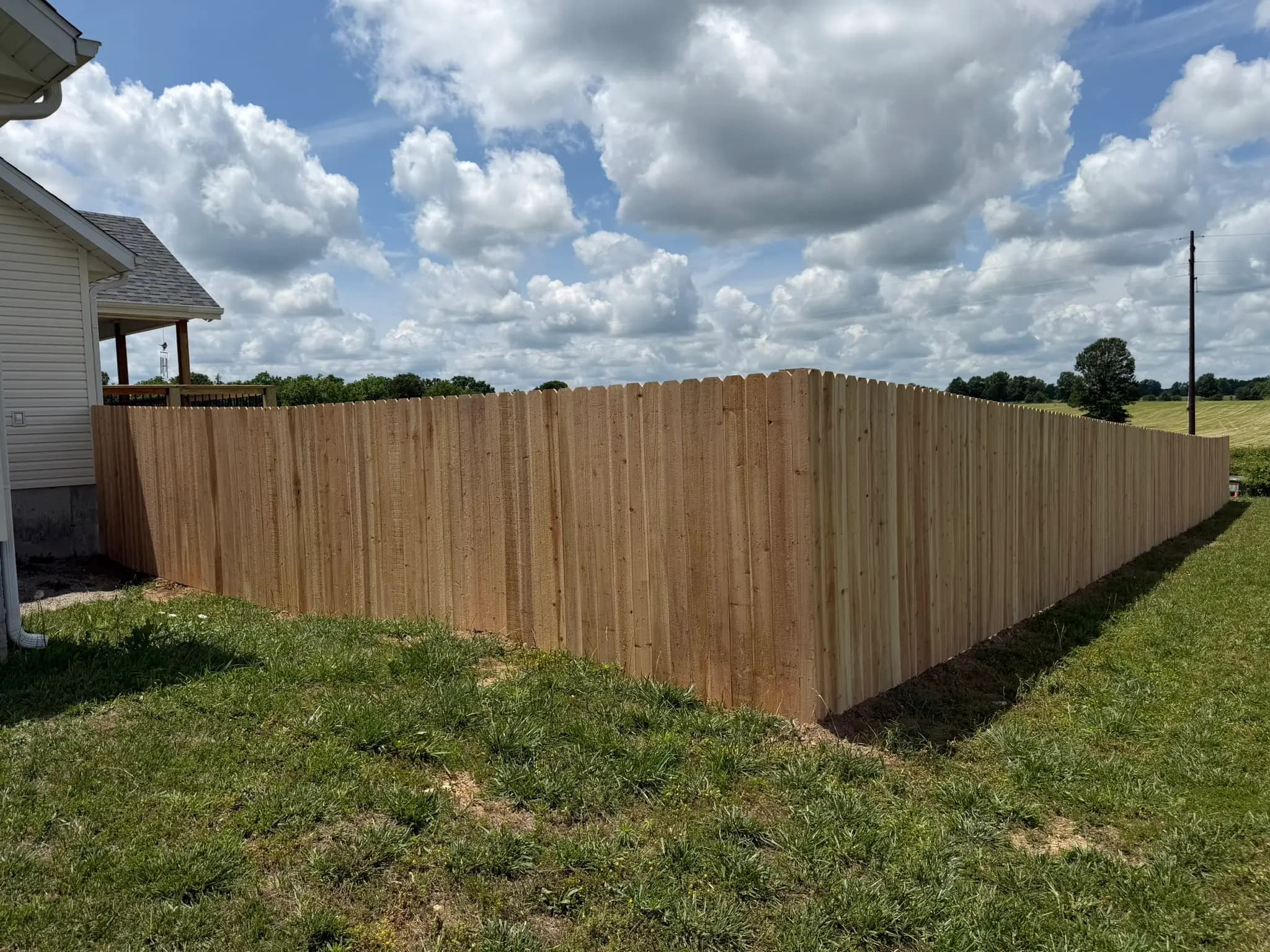 Wood privacy fence line beside a house and open field