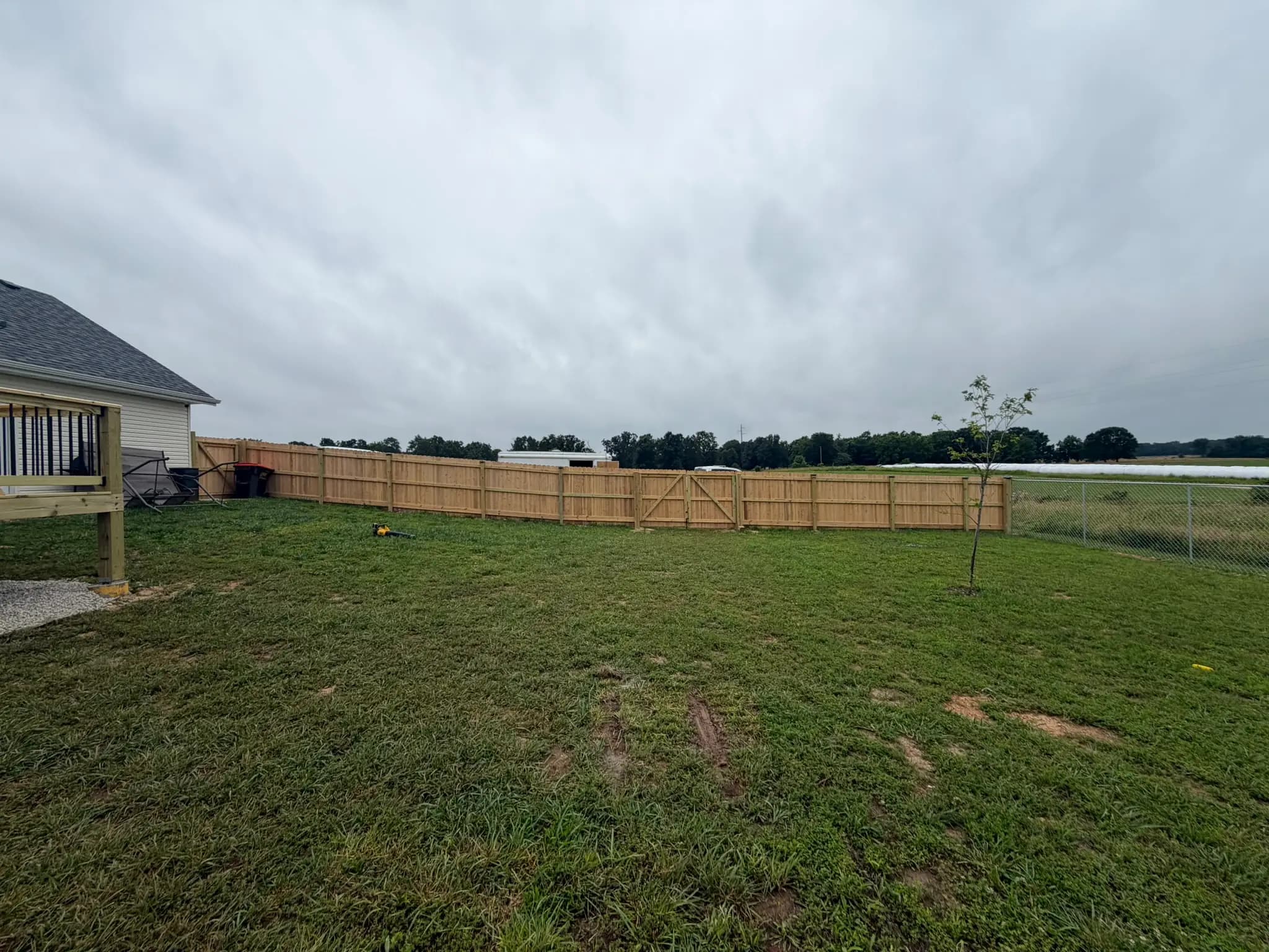 Backyard wood privacy fence across a wide lawn