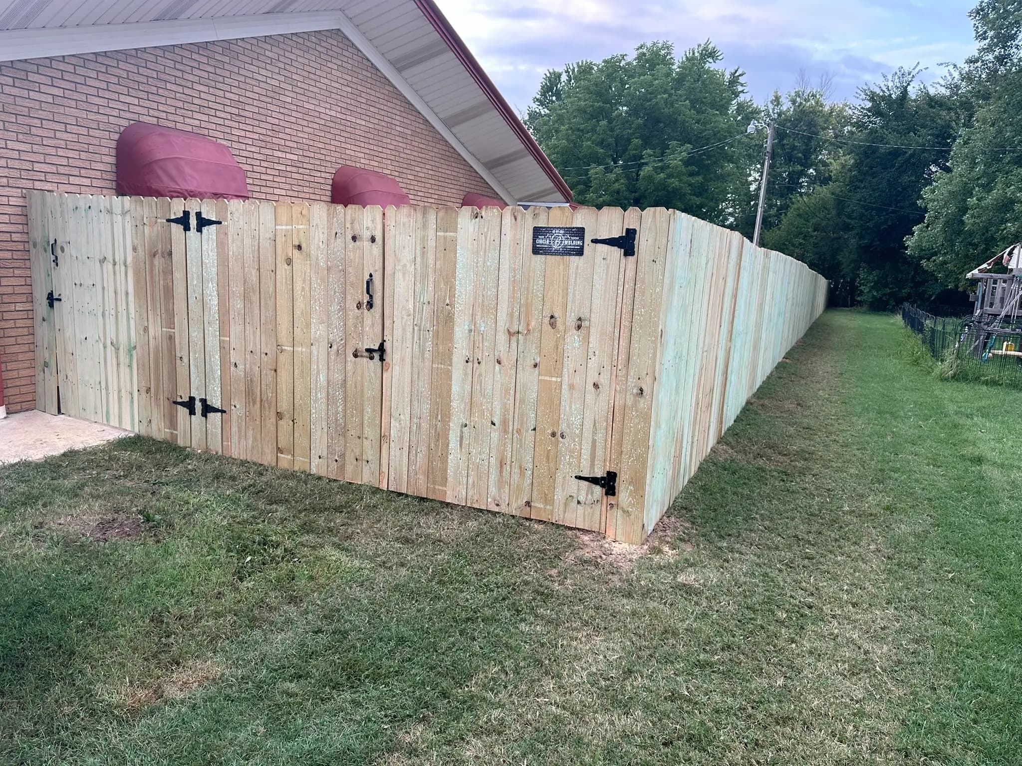 Wood privacy fence with gate beside a brick building