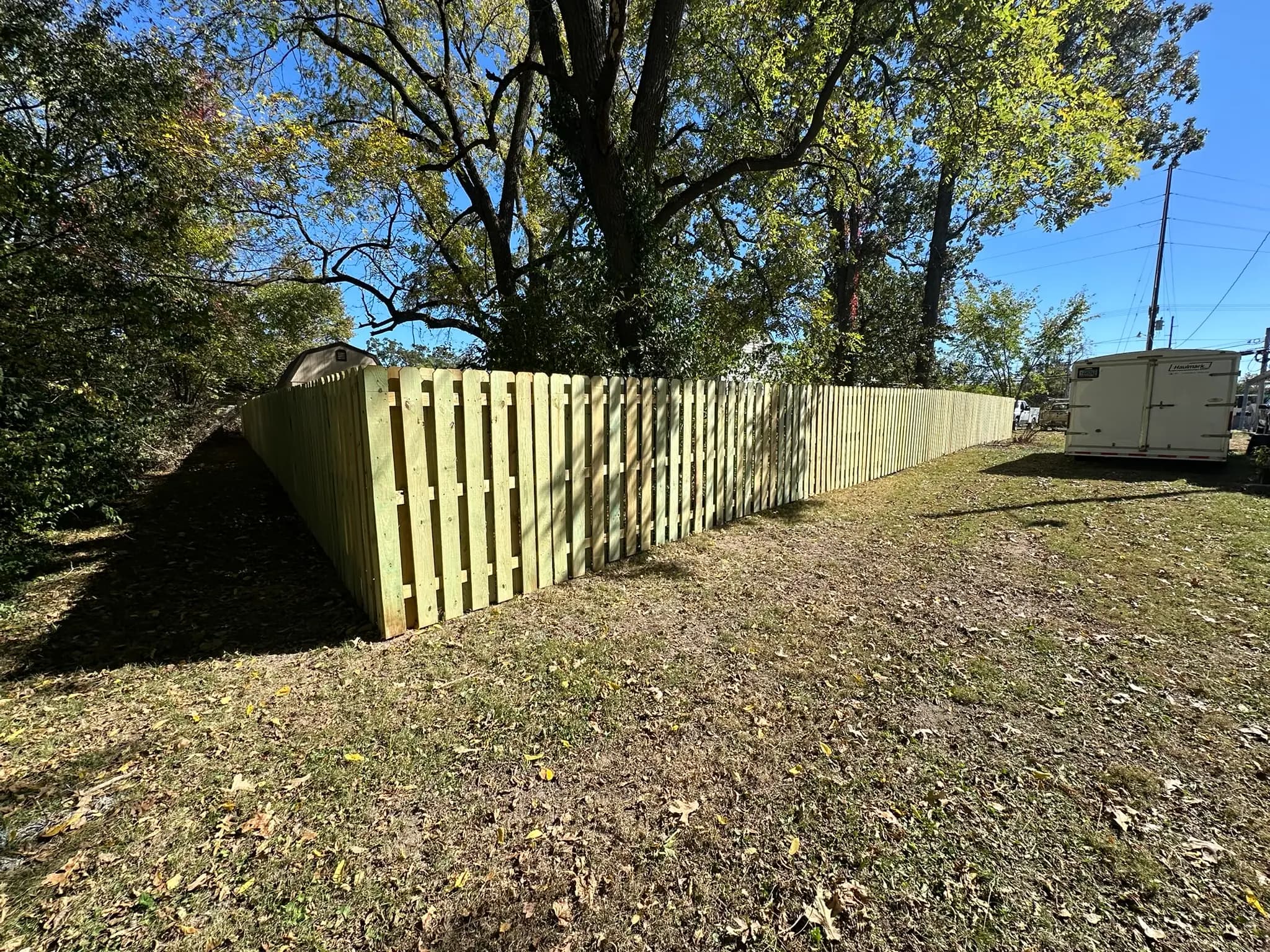 Wood privacy fence with diagonal corner run near trees