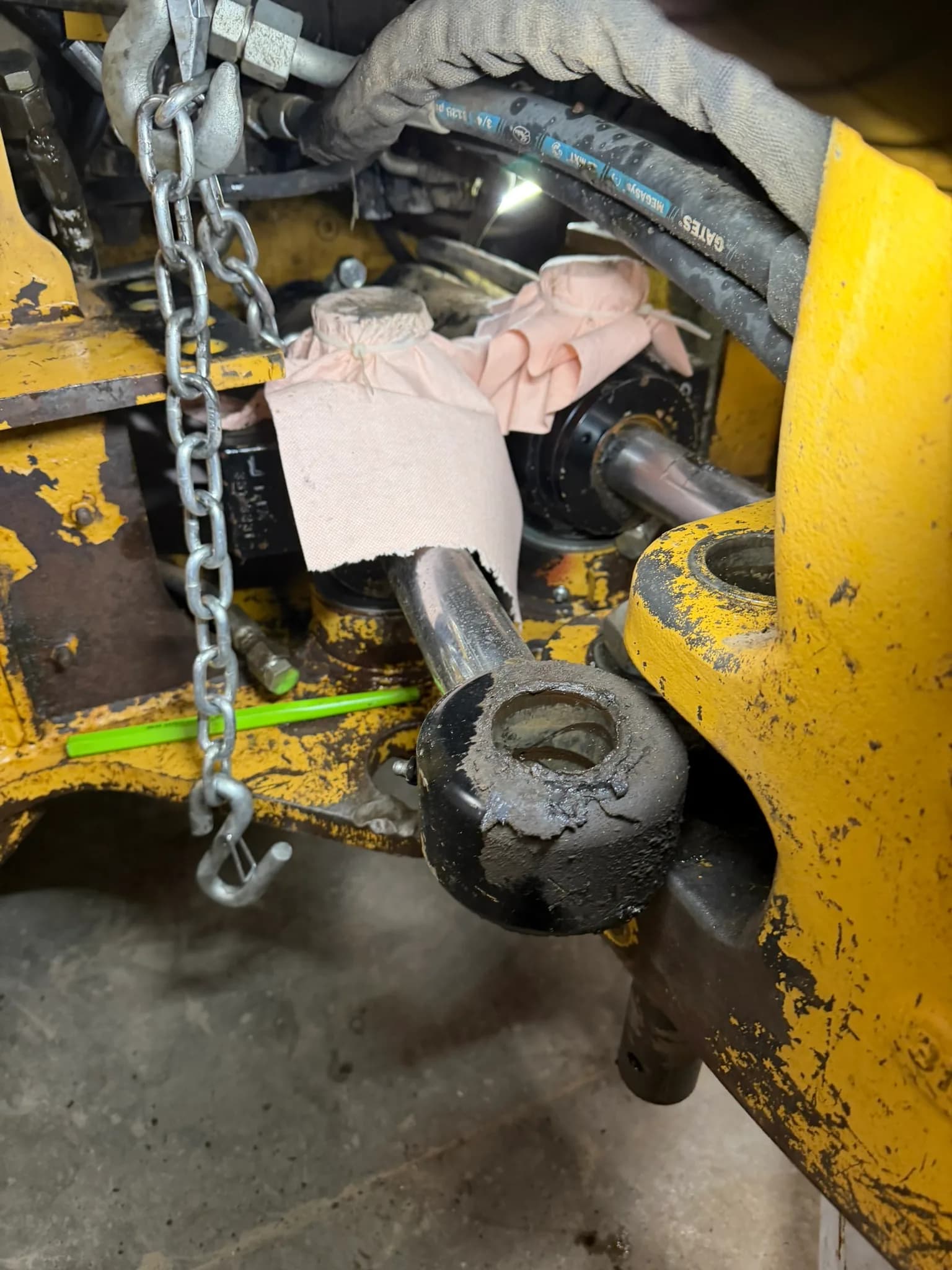 Hydraulic cylinder and linkage repair in progress on yellow heavy equipment