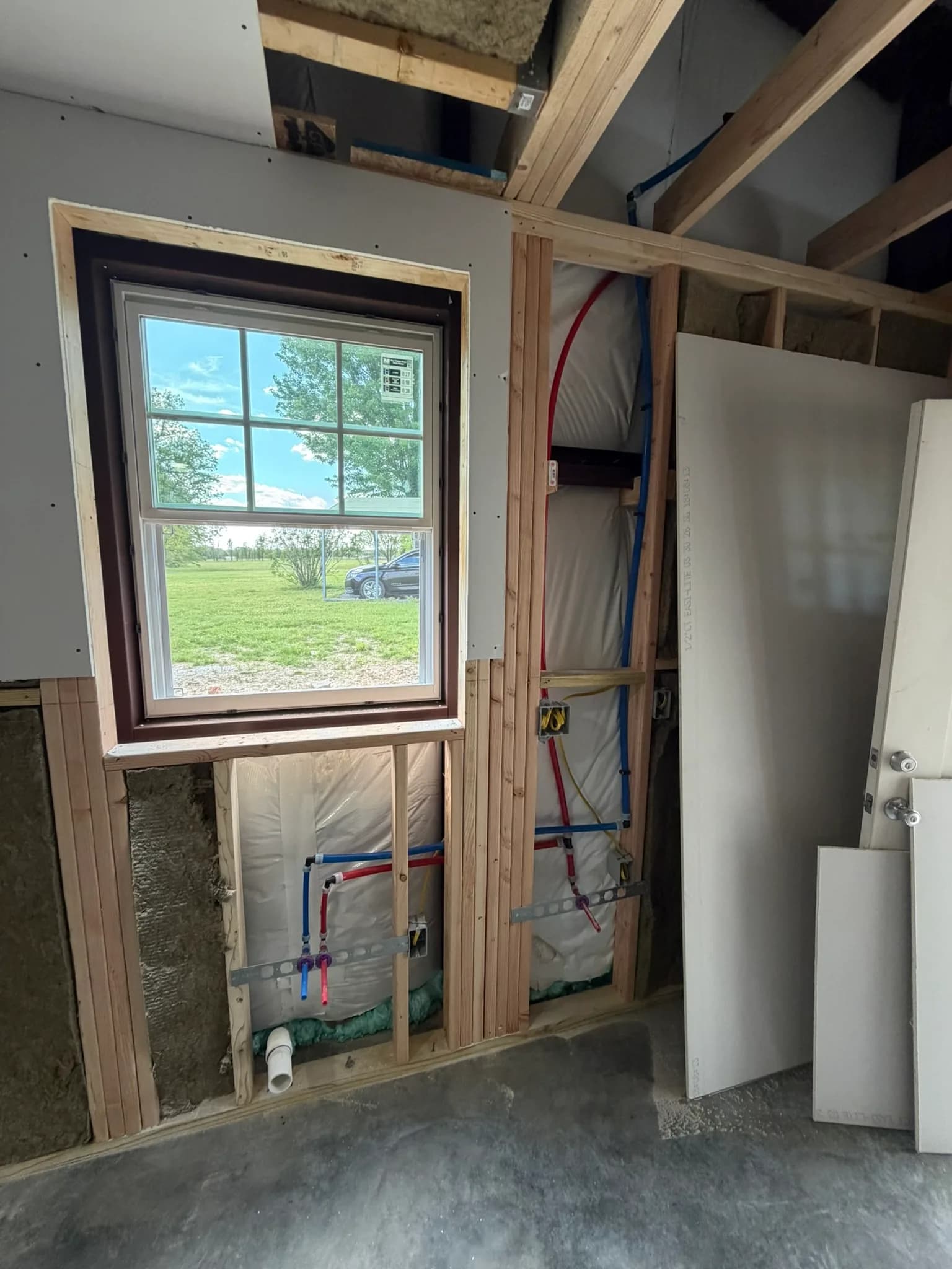 New window framing, insulation, and plumbing rough-in during a home remodel