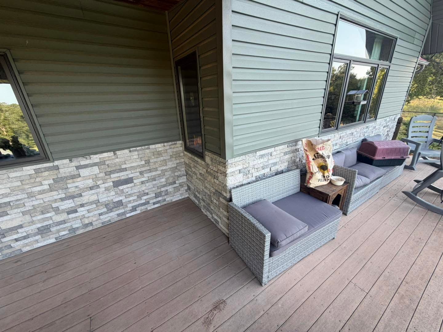 Finished gray brick wainscot wrapping a covered porch wall with outdoor seating