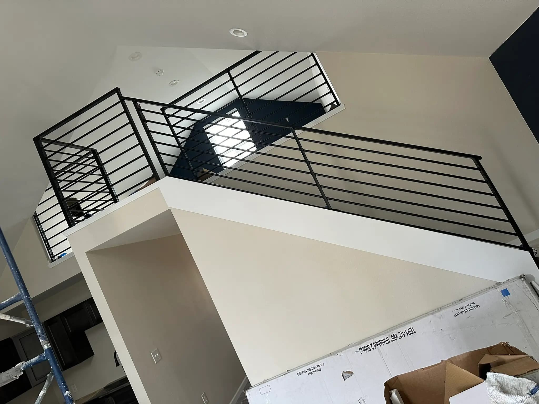 Black custom metal railing installed around an interior stair opening