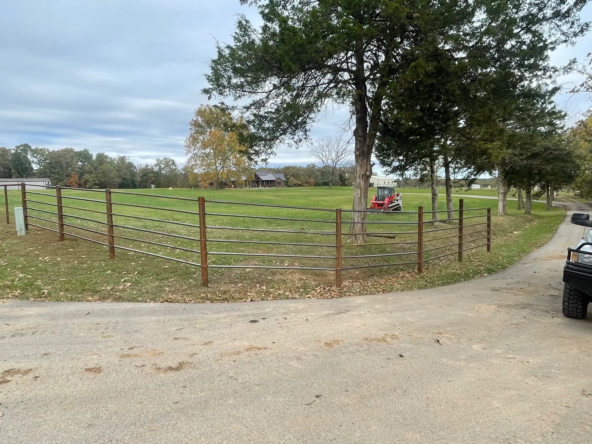 Pipe gate and farm fence line installed beside a driveway