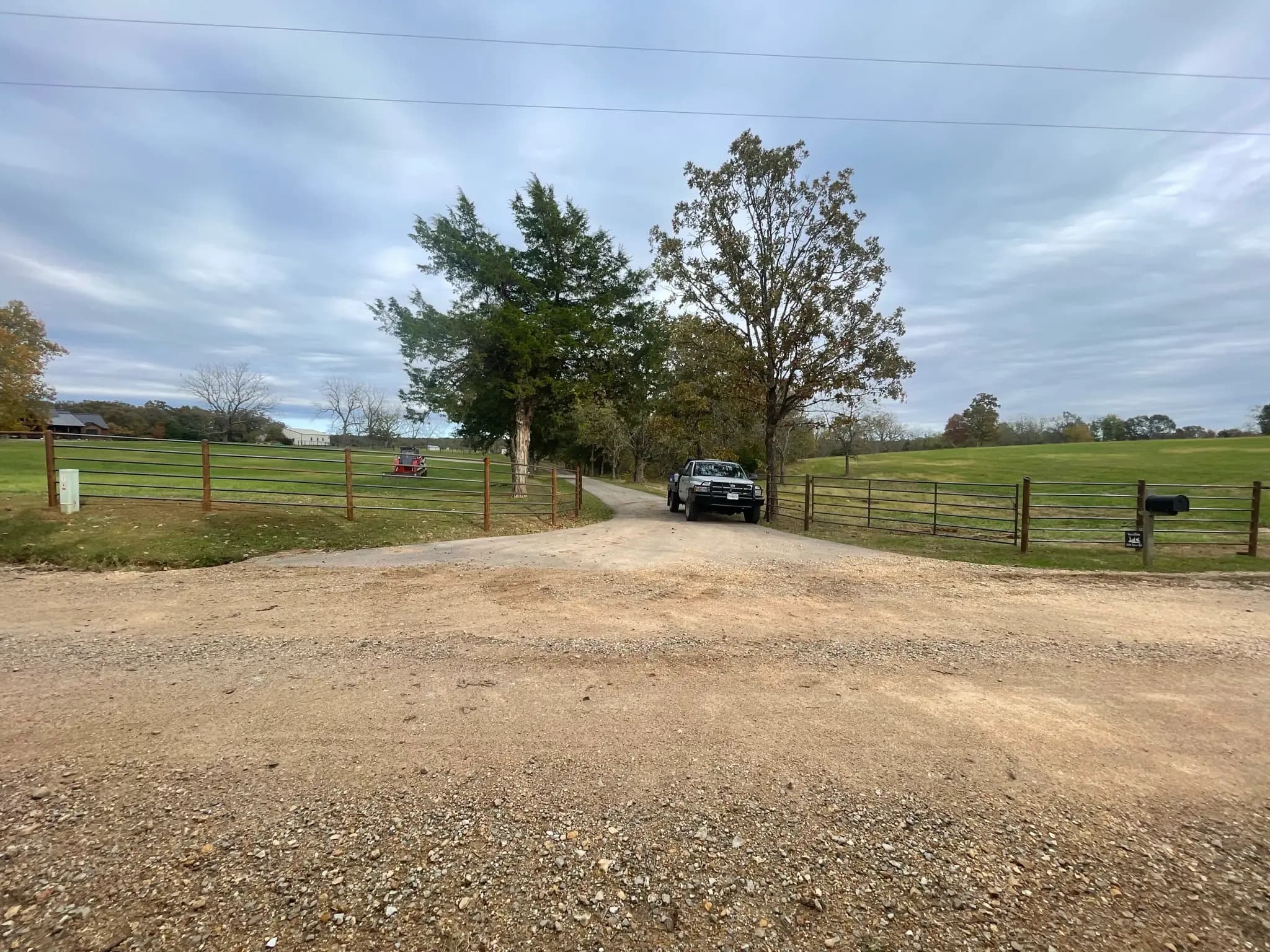 Farm driveway lined with pipe fence and welded gates